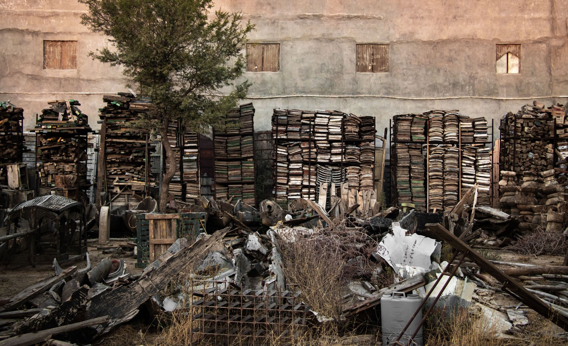 An organized clutter of discarded materials in an outdoor junkyard setting, evoking industrial decay.